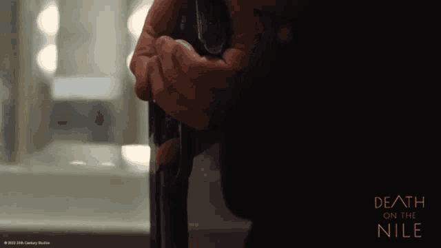 a poster for death on the nile showing a person holding a gun