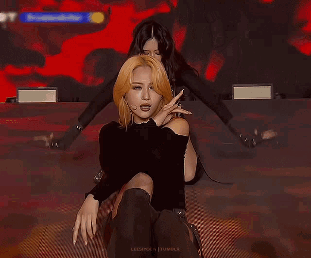 a woman with blonde hair is wearing a black turtleneck and a microphone