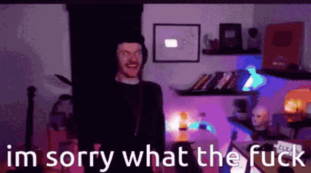 a man is standing in a dark room with the words im sorry what the fuck