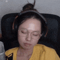 a woman wearing headphones and glasses is sleeping in a chair .