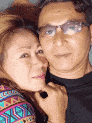 a man wearing glasses and a woman wearing a colorful shirt are posing for a picture