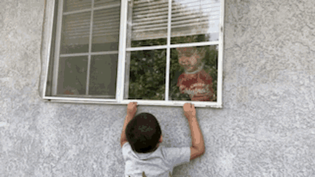 a young boy is looking out of a window with a reflection of a child wearing a red shirt that says coca cola