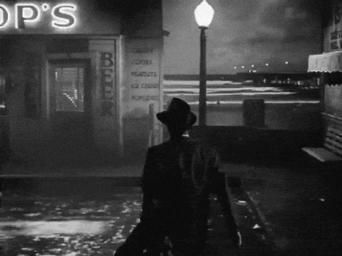 a black and white photo of a man walking in front of a shop called op 's