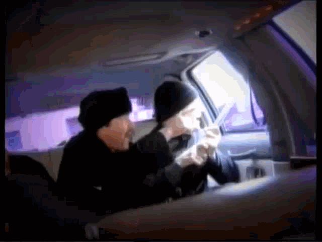 two people are sitting in the back seat of a car smoking