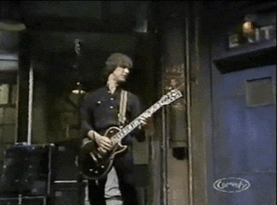 a man playing a guitar in front of a sign that says " comedy "