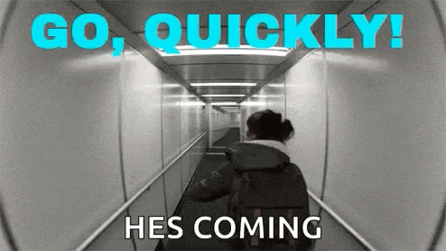 a woman is walking down a hallway with the words go quickly hes coming