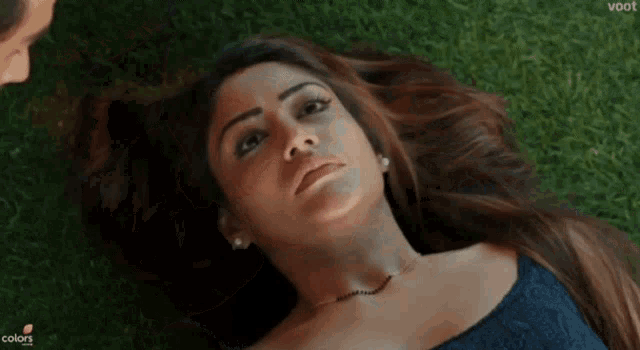 a woman is laying in the grass with a voot logo behind her