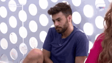 a man with a beard is sitting in front of a wall with polka dots on it .