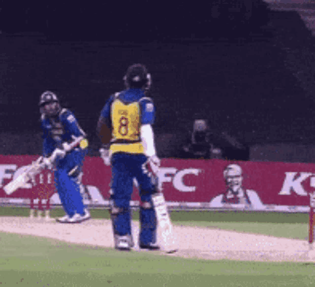 a cricket player with the number 8 on his back is standing on the field