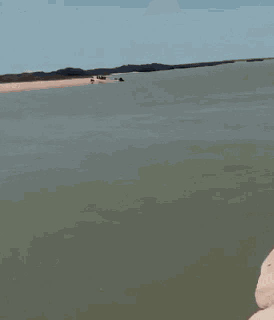 a group of men are fishing on a rocky shoreline near a body of water .