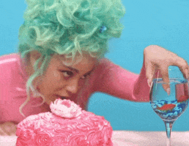 a woman with green hair is looking at a cake