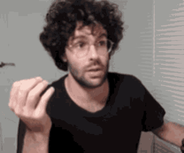 a man with curly hair and glasses is making a funny face