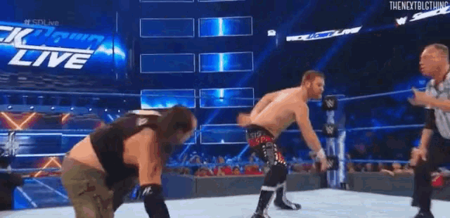 two men are wrestling in a wrestling ring with a referee .