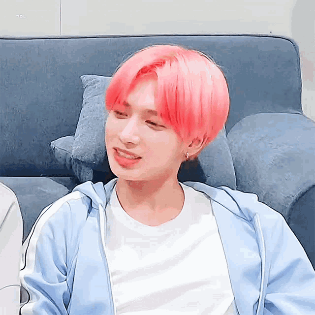 a boy with pink hair is sitting on a couch