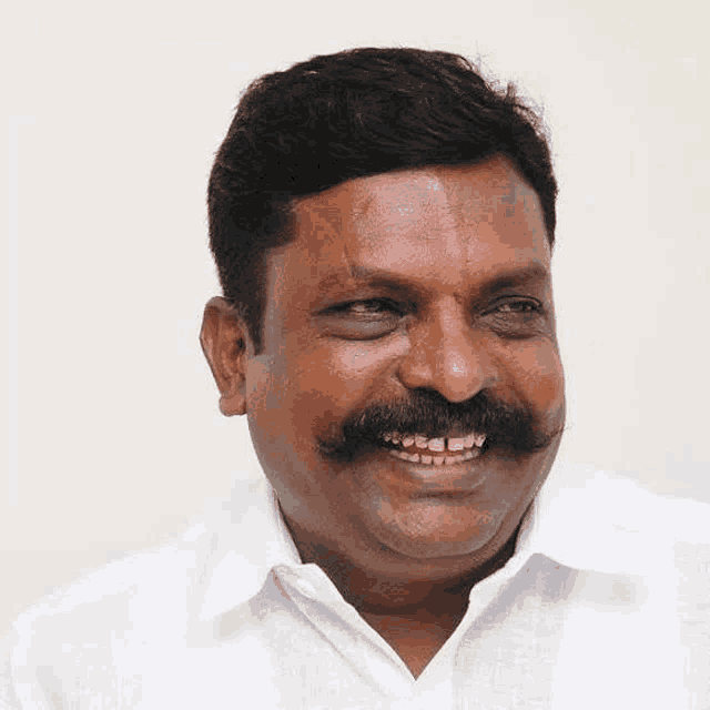 a man with a mustache and white shirt is smiling .