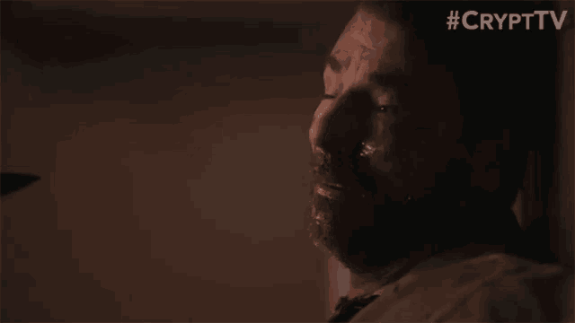 a man is laying in a dark room with a knife in his mouth .