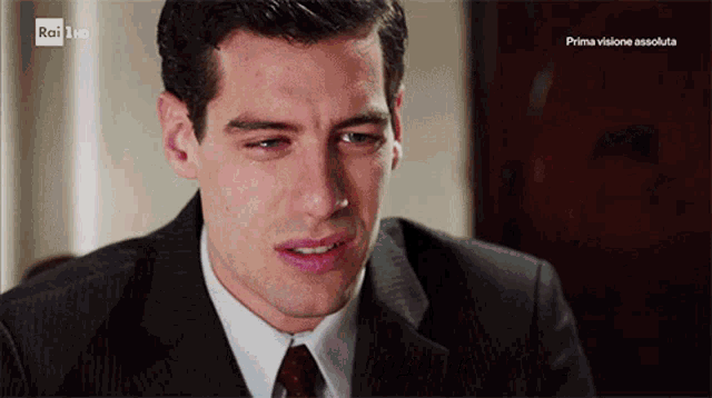 a man in a suit and tie is crying in front of a screen that says rai 1 hd