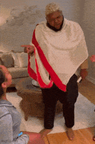 a man wearing a white cape with a red stripe is pointing at someone