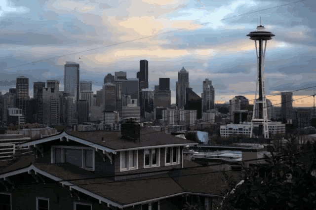 a city skyline with a few houses in the foreground and the space needle in the background