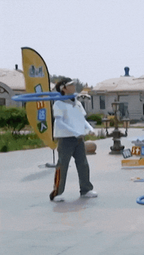 a man is holding a blue frisbee in front of a yellow flag that says ' a ' on it