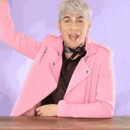 a man in a pink jacket is sitting at a table with the word in written on it .