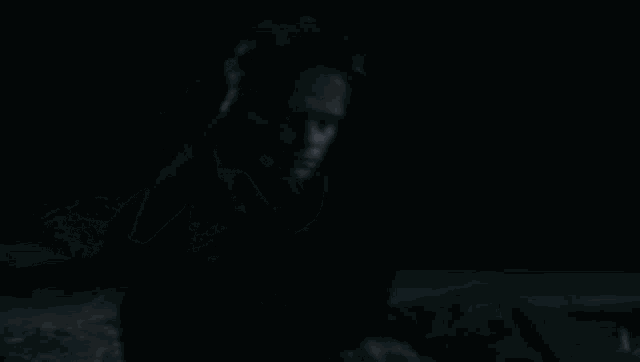 a man is laying on the ground with his head on his hand in the dark .