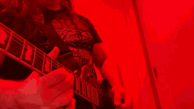 a person playing a guitar with a red background and a shirt that says ' guns n ' roses ' on it