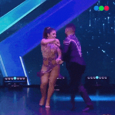 a man and a woman are dancing on a stage in front of a purple background