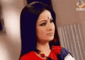 a woman with long black hair and a bindi on her forehead is sitting in a chair looking at the camera .