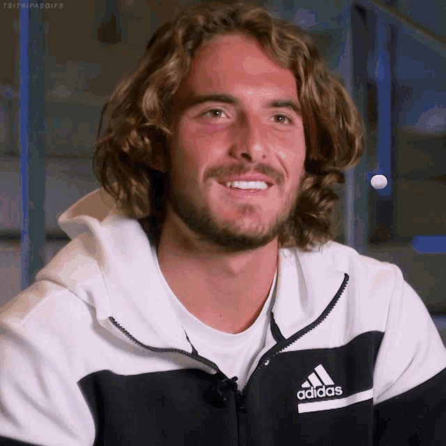 a man with long hair and a beard is wearing an adidas sweatshirt
