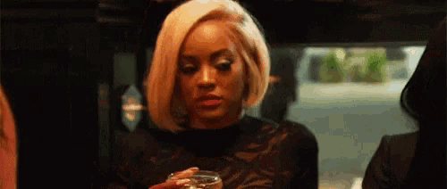 a woman in a black top is holding a glass of wine .