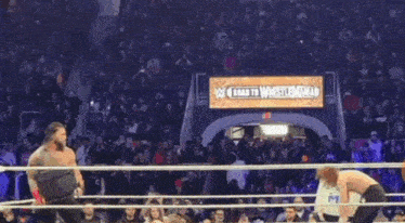 a crowd of people are watching a wrestling match in a ring while holding cell phones .