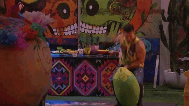 a man is sitting on a green bean bag chair in front of a wall with a skull on it