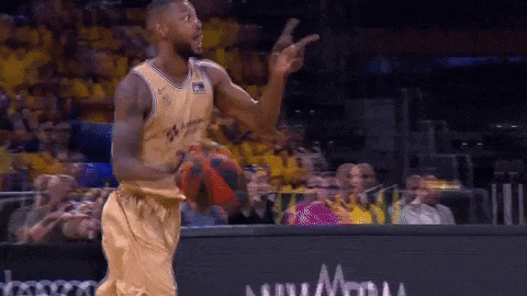 a man in a basketball uniform is pointing at something while holding a ball