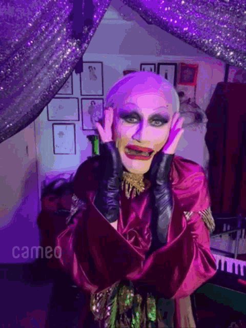 a drag queen wearing a purple robe and black gloves is making a funny face