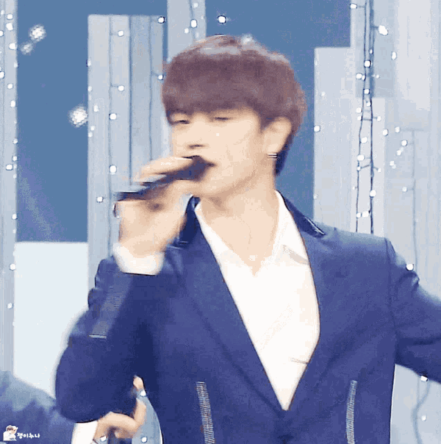 a man in a suit is singing into a microphone with the letters n on the bottom right