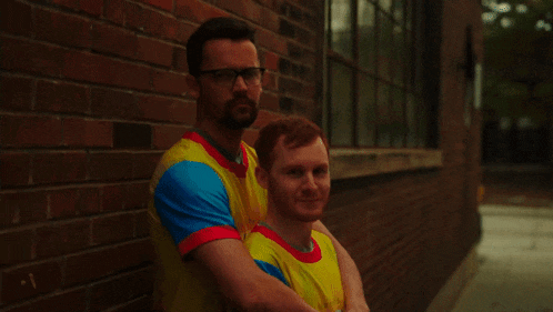 two men standing next to each other wearing colorful shirts