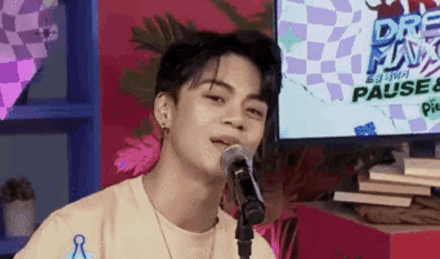 a young man is singing into a microphone in front of a screen that says dream man