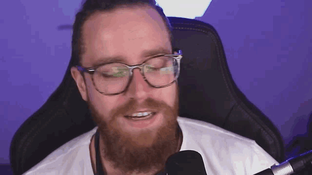 a man with glasses and a beard is sitting in a chair