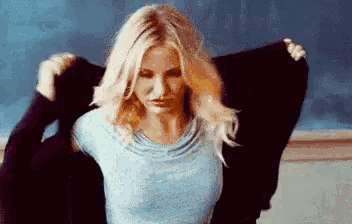 a woman is taking off her sweater in a classroom .