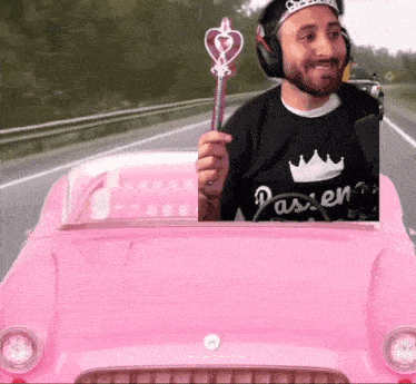 a man wearing headphones is driving a pink car and holding a wand with a heart on it