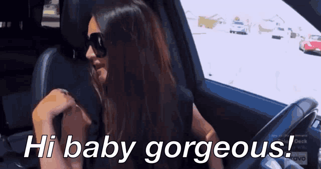 a woman wearing sunglasses is sitting in a car with the words hi baby gorgeous below her