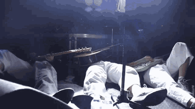 a person laying on a stage with a drum and a guitar