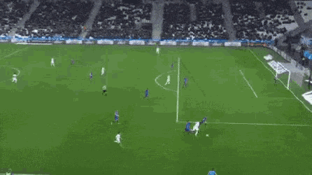 a soccer game is being played on a soccer field with a crowd watching .