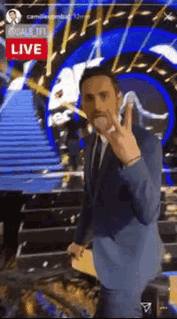 a man in a suit and tie is giving a peace sign while standing on a stage .