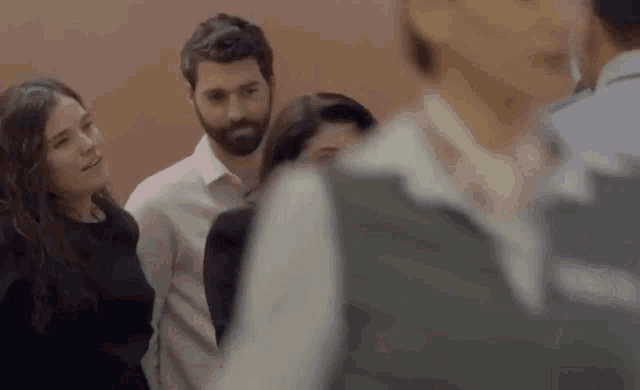 a group of people are standing in a room talking to each other .