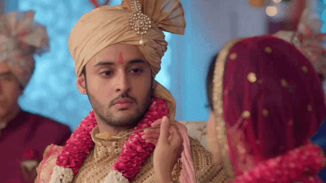 a bride is putting a garland on the groom 's head