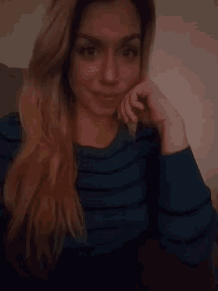 a woman with long blonde hair wearing a blue striped shirt