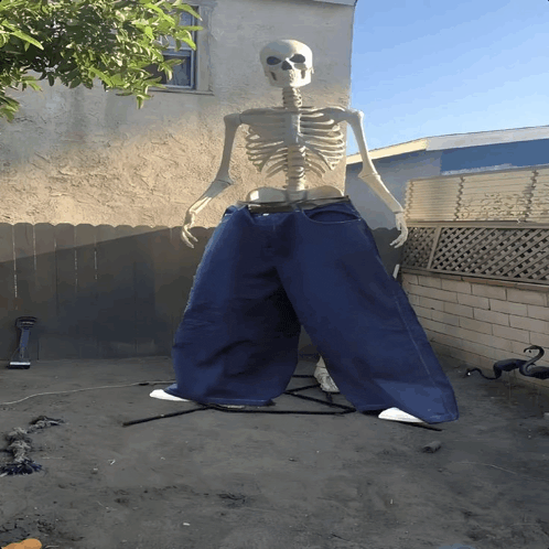 a skeleton wearing blue jeans is standing in front of a fence
