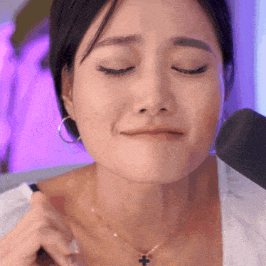 a woman wearing a necklace with a cross on it is making a funny face